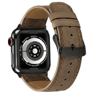 Een close-up van een zwarte Apple Watch met een DealFixers Leren Horloge Bandje in bruin echt leer, met zichtbare stiksels, een zwarte gesp, sensoren en gegraveerde tekst. Geschikt voor ALLE Apple Watch 42/44/45/49mm Series 1-10 & SE.