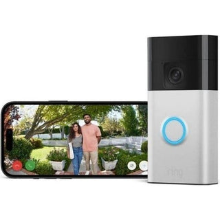 Een smartphone toont een video van twee mensen buiten bij een RING Ring Battery Video Doorbell Staal, een draadloze deurbel met een oplichtende blauwe knop. Bomen en groen zijn zichtbaar op de achtergrond.