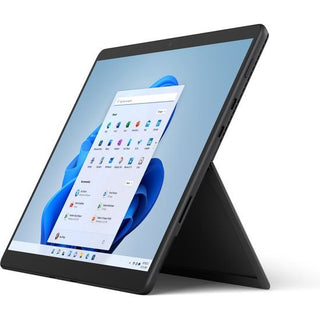 Een Microsoft Surface Pro 8 (i5, 8GB, 256GB SSD) in Graphite wordt schuin getoond met de ingebouwde kickstand. Het display toont het Windows 11 startmenu en apps op een lichtblauwe achtergrond.