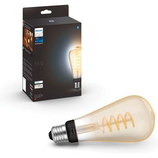 Een Philips Hue gloeidraad-edisonlamp ST64 van Philips ligt voor zijn doos, waarop de slanke slimme lamp en productdetails worden weergegeven. De lamp gloeit warm.