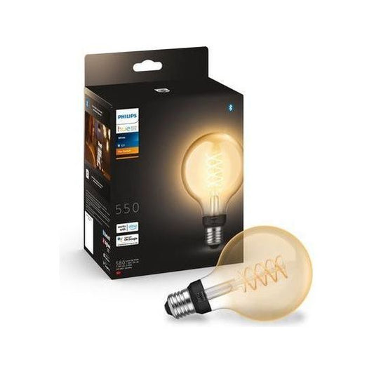 De Philips Hue gloeilamp G93 van Philips, met een E27 fitting en zichtbare spiraalvormige gloeidraad, wordt getoond naast de zwarte verpakking met een afbeelding en details van de decoratieve LED-lamp die warm wit licht geeft.