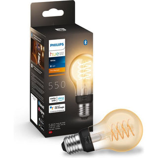 Een Philips Hue filament standaardlamp A60 van Philips is afgebeeld naast de verpakking, waarop de lamp, het Bluetooth-logo en de compatibiliteit met Alexa en Google Assistant te zien zijn. De decoratieve E27 lamp heeft een zichtbare spiraalvormige gloeidraad.