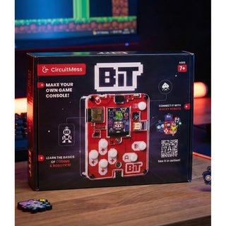 Een doos met het DealFixers Retro Gaming Handheld (Zelfbouw / Bouwpakket) bouwpakket staat op een bureau en toont de geassembleerde console en functies zoals retrogames, basiscodering en programmeren in MicroPython. Een computerscherm en figuurtjes staan op de achtergrond.