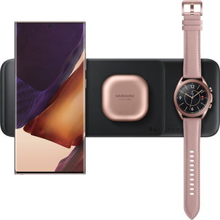 Een SAMSUNG Draadloze Oplader Trio (Zwart) houdt een smartphone rechtop, met een roségoud Galaxy Buds hoesje in het midden en een bijpassende Galaxy Watch die plat ligt - perfect om al je Samsung-apparaten samen op te laden.