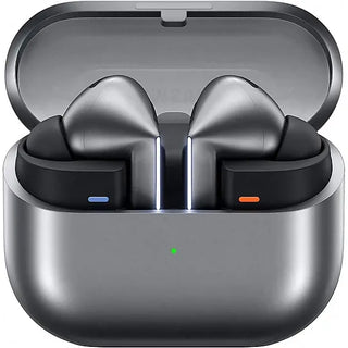 Een paar SAMSUNG Galaxy Buds3 Pro draadloze oordopjes in metallic grijs rusten in een open oplaadhouder met een groen indicatielampje. De comfortabele oordopjes zijn voorzien van blauwe en oranje lampjes, wat zorgt voor een opvallend, lichtgevend ontwerp.